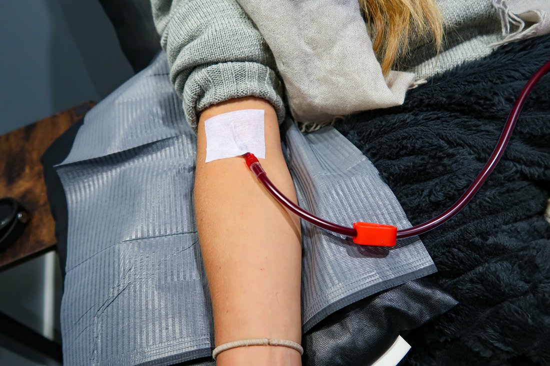 A patient's arm with the IV line placed, resting on a blanket